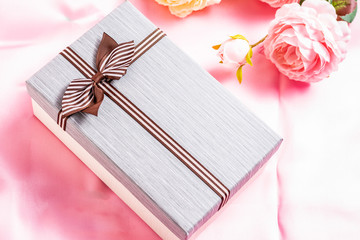 Beautiful gift box with roses on a pink fabric background