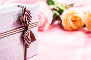 Beautiful gift box with roses on a pink fabric background