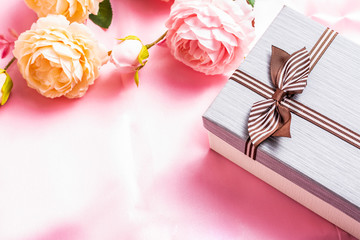 Beautiful gift box with roses on a pink fabric background