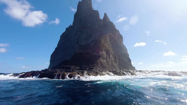 End view of Ball&rsquo;s Pyramid showing many birds flying overhead in slow motion
