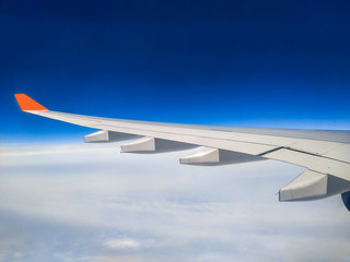 wing of airplane flying above clouds