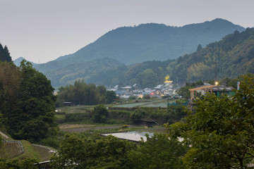 Fototapeta premium Rice fields and buildings in small Japanese mountain town at dusk