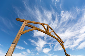 Low angle view of wooden gateway entrance to ranch against a blue sky
