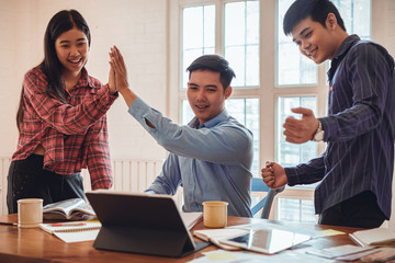 Successful young three colleagues creative designer startup teamwork giving a high fives gesture as they laugh and cheer their success. Designer Meeting Colleague Teamwork Occupation Concept
