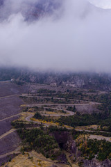 Scene view of a road going up in the mountain reaching clouds covering it
