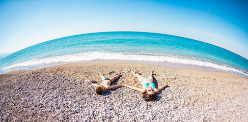 The boy with his mother sunbathe on the beach.