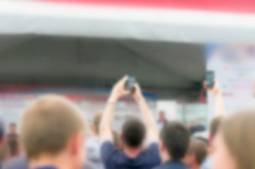 Blurred People Raised Hands with Smartphones Recording the Event.