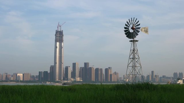 Multi-bladed windpump in middle of Hankou marshland and Wuhan city skyline in background in Hubei China