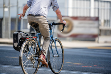 Cyclist rides bicycle along city street and shows with his hand maneuver turning at an intersection
