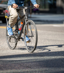 Fototapeta premium Cyclist rides bicycle with basket at the back along city street