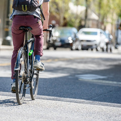 Naklejka na ściany i meble Cyclist rides bicycle on city street friendly to cycling