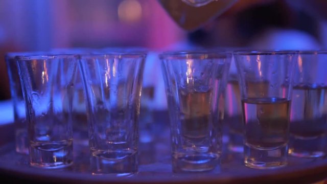 Pouring shots of vodka in slow motion during party. Close up shot