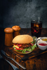Delicious home made hamburger with beef, ketchup, mustard and fresh vegetables served on wooden board. Free space for text