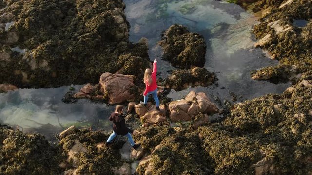 Two girls in Ireland climb over the rocky oceanfront of Malin Head - travel photography
