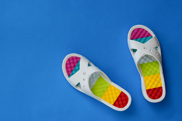 Colorful women's flip-flops on a blue background. The concept of a holiday by the sea. Flat lay.