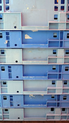 Old agriculture plastic containers in faded color of blue, stacked together one above another.
