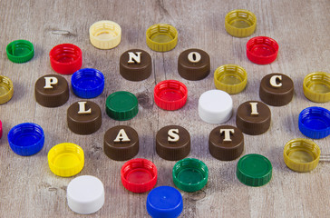 No plastic. Inscriptions in wooden letters on plastic bottle caps.