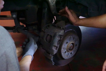 car mechanic screwing the wheel at auto repair garage