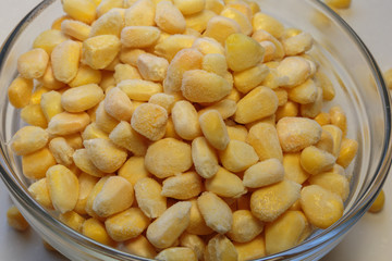 Bowl with frozen corn kernels on white background.