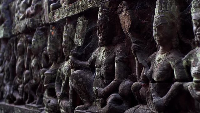 Close view of detailed and cracked by time bas-reliefs of the Leper King terrace located in the northwest corner of the Royal Square of Angkor Thom, Cambodia.