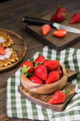 Strawberry in wooden bowl on wooden background. Rustic style