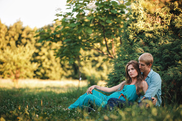 Young beautiful family, future parents. Pregnant woman in the park outdoors. Calm pregnant woman in third trimester. Walking in public garden.