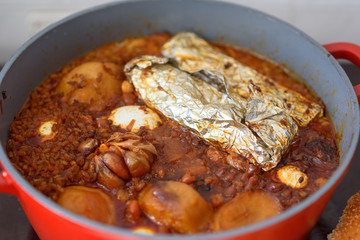 Hot plate for the Sabbath, a pot of spicy meat cooked with potatoes, barleys, jachnun,garlic,wheat and eggs. Pot of cholent Hamin in hebrew, top view. Traditional food Jewish Shabbat.