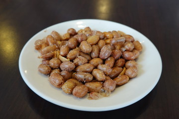 A plate of salted peanuts is on the table. A common side dish in Taiwanese restaurants. Food concept. Peanuts are rich in essential nutrients.