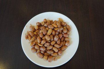 A plate of salted peanuts is on the table. A common side dish in Taiwanese restaurants. Food concept. Peanuts are rich in essential nutrients.
