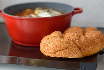 Hot plate for the Sabbath, a pot of spicy meat cooked with potatoes, barleys, wheat and eggs. Pot of cholent Hamin in hebrew, challah-special bread in Jewish cuisine. Traditional food Jewish Shabbat.