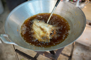 Chef cooking deep-fried fish in the big pan to Chinese banquet food preparation. fat from trans-fat concept. disease from cholesterol and Trans-fatty concept. image for copy space and objects.