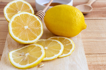 Fresh lemon with honey into white bowl on wood table.