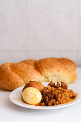 Challah Shabbat bread and hamin or cholent in hebrew - Sabbath traditional food on white table in the kitchen.