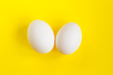 Two white eggs on a yellow background. Creative concept in the style of minimalism