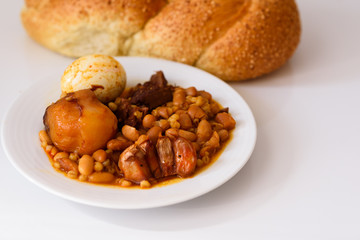 Challah Shabbat bread and hamin or cholent in hebrew - Sabbath traditional food on white table in...
