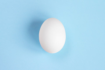 One white egg on a blue background. Creative concept in the style of minimalism. Birth boy concept with copy space close up