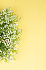 a bouquet of lilly of the valley isolated on yellow background, template for birthday or valentine's card