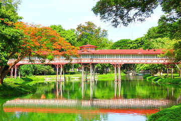 red wood walk way over pool at Sanam Chan Palace  Nakorn Pathom.the beautiful vitage bridge in red color with reflex in green area.