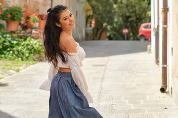 Fototapeta premium Happy beautiful woman in summer dress walking and running joyful and cheerful smiling in old town, Italy.