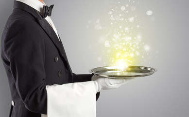 Elegant young waiter serving mysterious light on tray
