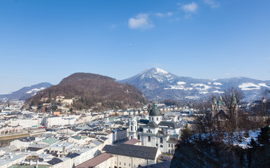 The view across Salzburg's Old Town in Austria.  Collegiate Church can be seen in the foreground and in the background are Kapuzinerberg hill and Gaisberg mountain.