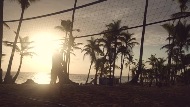 Sunrise on tropical beach, friends playing beach volleyball