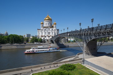 Fototapeta na wymiar The Cathedral of Christ the Savior and the Patriarchal bridge. Pleasure boat floats on the Moscow river on a Sunny summer day. Moscow, Russia