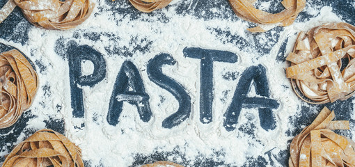 Homemade uncooked pasta on black background. Making fresh italian fettuccine.