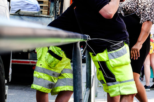 Stockholm, Sweden Workmen Standing By The Side Of The Road Almost Mirroring Each Other.