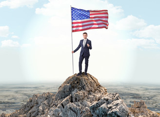 Successful businessman on the top of a mountain holding victory flag
