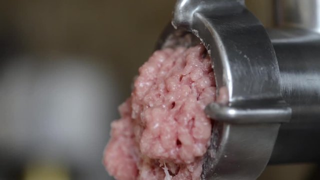 Meat is grinded in a meat grinder. Pare raw meat falls from the electric meat grinder 