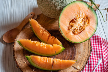 Fresh of whole and sliced orange melon or cantaloupe on wooden cutting board and background wooden table. Favorite fruit in summer concept.