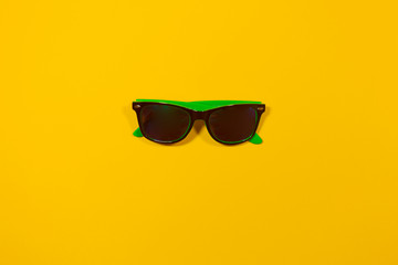 One pair of vacation sunglasses are laying on a yellow surface