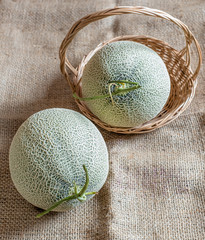 Fresh of whole orange melon or cantaloupe on burlap fabric sack background and wooden table....